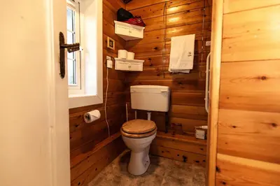 a bathroom with a toilet in a wooden wall at Rustic Log cabin in Snowdonia By Seren Short Stays in Trawsfynydd