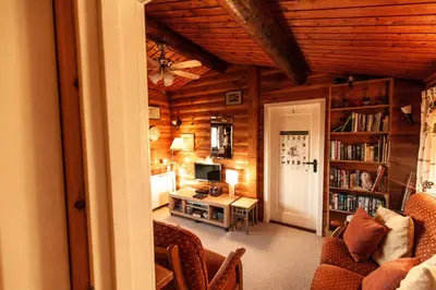 a living room with a couch and a desk with a computer at Rustic Log cabin in Snowdonia By Seren Short Stays in Trawsfynydd