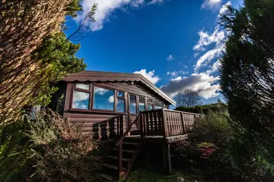 a small cabin with a porch and windows on a field at Log Cabin nr Coed y brenin By Seren Short Stays in Trawsfynydd
