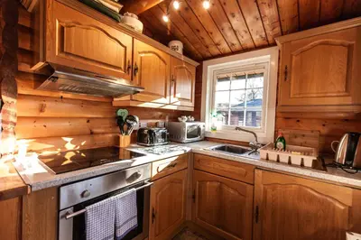 a kitchen with wooden cabinets and a stove top oven at Log Cabin nr Coed y brenin By Seren Short Stays in Trawsfynydd