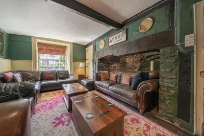 a living room with leather furniture and a stone fireplace at The Boars Head Pub in Bishops Castle