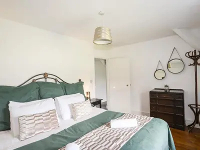 a bedroom with a green bed with white pillows at Glyn Morfa in Harlech