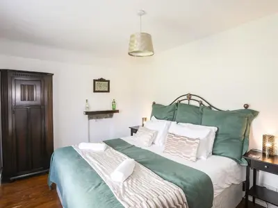 a bedroom with a large green bed with white pillows at Glyn Morfa in Harlech