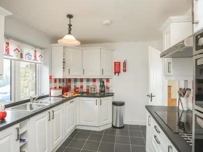 a kitchen with white cabinets and a sink at Red Ridge in Harlech
