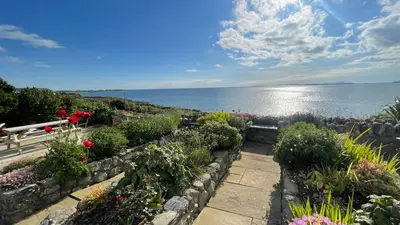 a garden with flowers and a view of the water at Red Ridge in Harlech