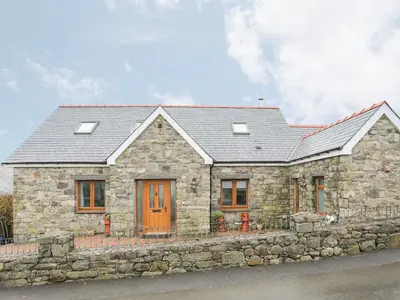 a stone house with a stone wall at Red Ridge in Harlech