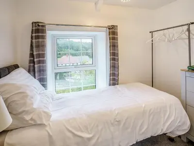 a bedroom with a white bed and a window at Fron Towyn Cottage in New Quay