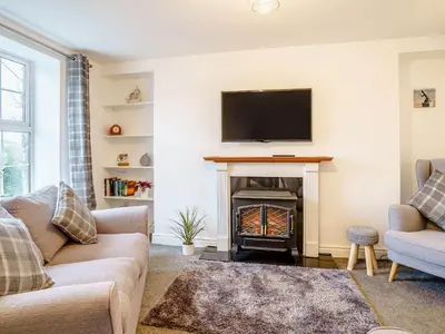 a living room with a fireplace with a tv on the wall at Fron Towyn Cottage in New Quay