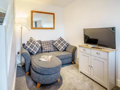 a living room with a couch and a tv at Fron Towyn Cottage in New Quay
