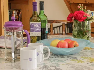 a table with two bottles of wine and a bowl of apples at Minton Lane Cottage in Church Stretton