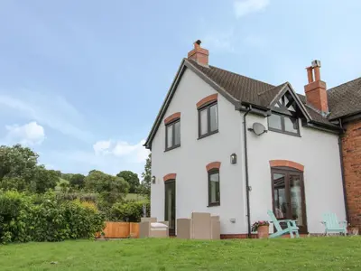 a white house with a lawn in front of it at Minton Lane Cottage in Church Stretton