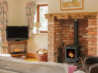 a living room with a fireplace and a tv at Minton Lane Cottage in Church Stretton