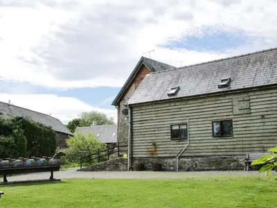 an old wooden building with a bench in front of it at Broughton Stables in Montgomery