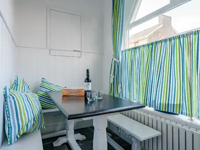 a room with a table and a window with a bottle of wine at Ystwyth House in Borth