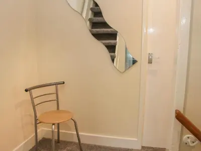 a stairway with a chair and a mirror at Whitewater Cottage in Llangollen