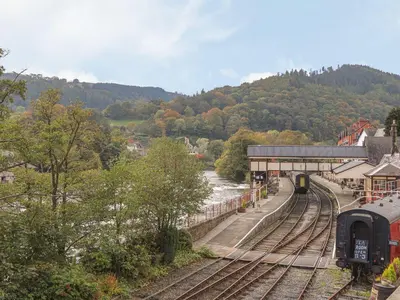 a train station with a train on the tracks at Whitewater Cottage in Llangollen