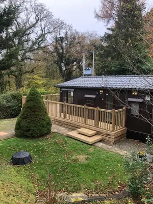 a cabin with a wooden deck and a house at 8F Lakeside Lodge Caer Beris Builth Wells - No Tradesman in Builth Wells