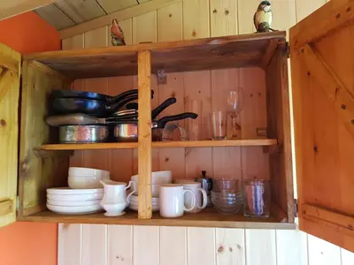 a wooden cabinet with cups and dishes on it at Cozy Cabin Retreat - Sleeps 2 & a Child in Craven Arms