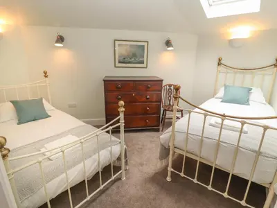 a bedroom with two beds and a wooden dresser at Cwmalis Hall in Llangollen