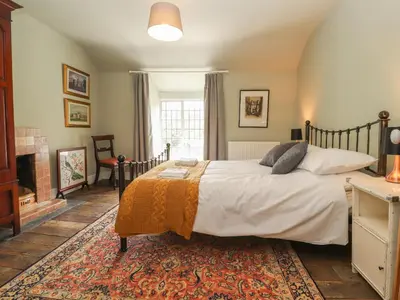 a bedroom with a large bed and a fireplace at Cwmalis Hall in Llangollen