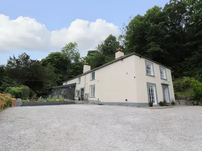 a white house with a gravel driveway at Cwmalis Hall in Llangollen