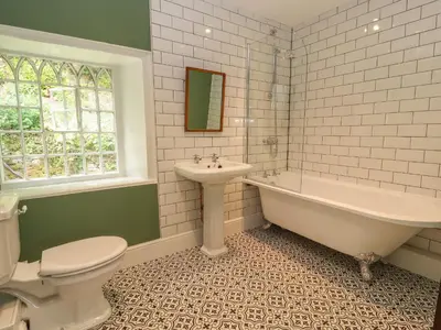 a bathroom with a tub and a toilet and a sink at Cwmalis Hall in Llangollen