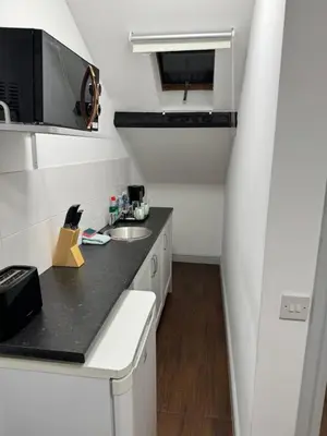 a small white kitchen with a sink and a microwave at The Radnorshire Arms Hotel in Presteigne