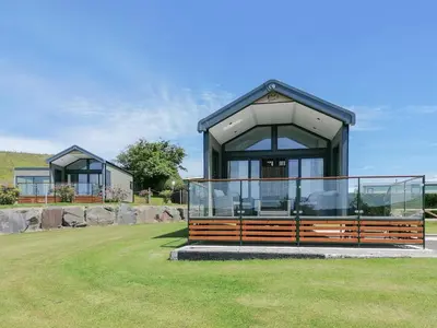 a house with a large glass door on the grass at Lake Vyrnwy Luxury Pod in Llanwddyn