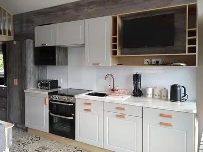 a kitchen with white cabinets and a stove top oven at Lake Vyrnwy Luxury Pod in Llanwddyn