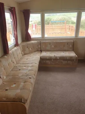 a long couch in a room with windows at Hill View caravans in Aberystwyth