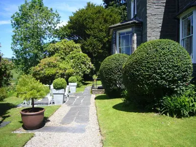 a garden with chairs and bushes and a house at Cae'r Blaidd Country House in Ffestiniog