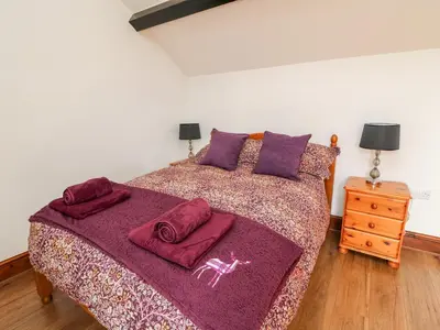 a bedroom with a large bed with purple blankets and pillows at Green Cottage in Rhayader