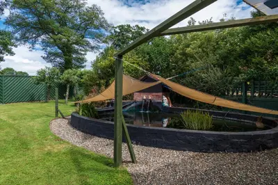 a hammock in a garden with a pond at Finest Retreats - The Grove Annexe in Craven Arms