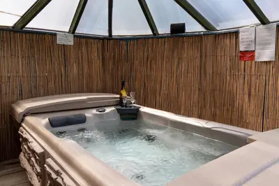 a jacuzzi tub with a bottle of wine in it at Finest Retreats - The Grove Annexe in Craven Arms