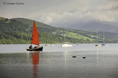 a small boat with a red sail in the water at 5 Bed in Bala oc-bow163 in Bala
