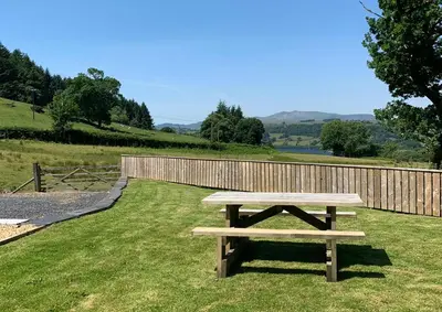 a wooden picnic table in the grass near a fence at 3 Bed in Bala oc-bow162 in Bala