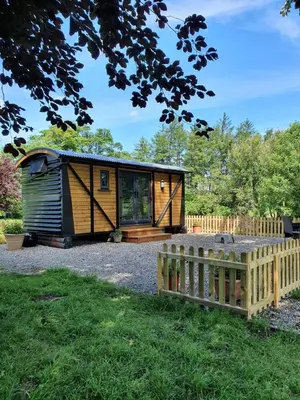 a small wooden cabin with a fence in a yard at Woodpeckers in Llandrindod Wells