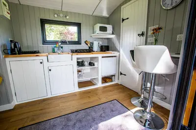 a small kitchen with white cabinets and a sink at Woodpeckers in Llandrindod Wells