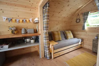 a room with a couch in a log cabin at Torrent Walk Glamping Huts in the Heart of Snowdonia in Dolgellau
