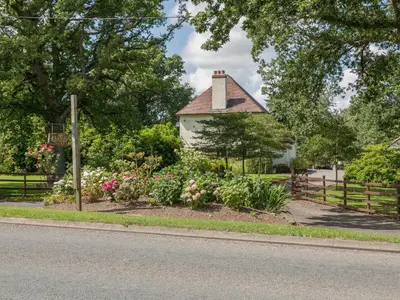a garden in front of a white house with flowers at The Big Dingle in Church Stretton