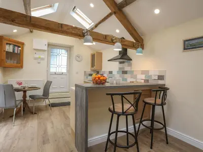a kitchen and dining room with a counter and stools at Glan Meon Cottage in Barmouth