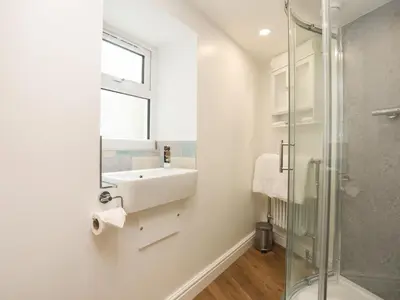 a bathroom with a sink and a glass shower at Glan Meon Cottage in Barmouth
