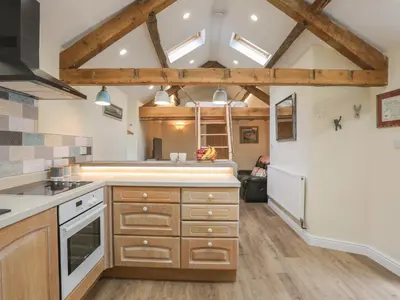 a kitchen with wooden cabinets and a ceiling with skylights at Glan Meon Cottage in Barmouth