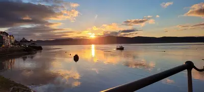 a sunset on a river with a boat in the water at The Old Stables Aberdyfi apartment 3 in Aberdyfi