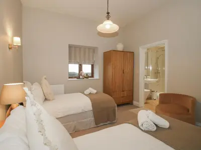 a bedroom with two beds and a chair at The Park in Craven Arms