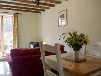 a living room with a wooden table with a vase of flowers at Y Bwthyn-Uk31367 in Tregynon