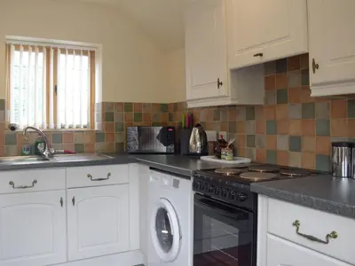 a kitchen with white cabinets and a dishwasher at Y Bwthyn-Uk31367 in Tregynon