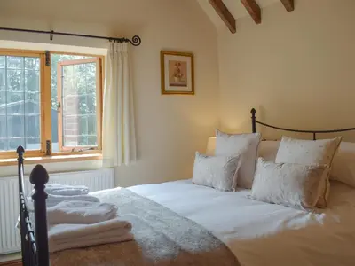 a bedroom with a bed with white sheets and a window at Y Bwthyn-Uk31367 in Tregynon