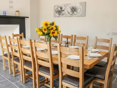 a wooden table with chairs and a vase of sunflowers at The Farm in Presteigne