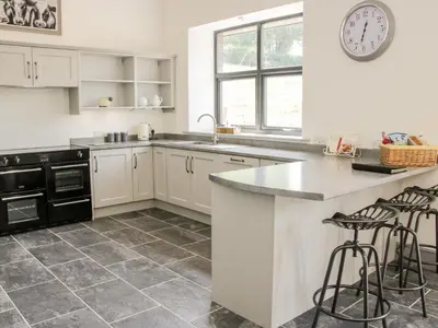 a kitchen with white cabinets and a counter with stools at The Farm in Presteigne